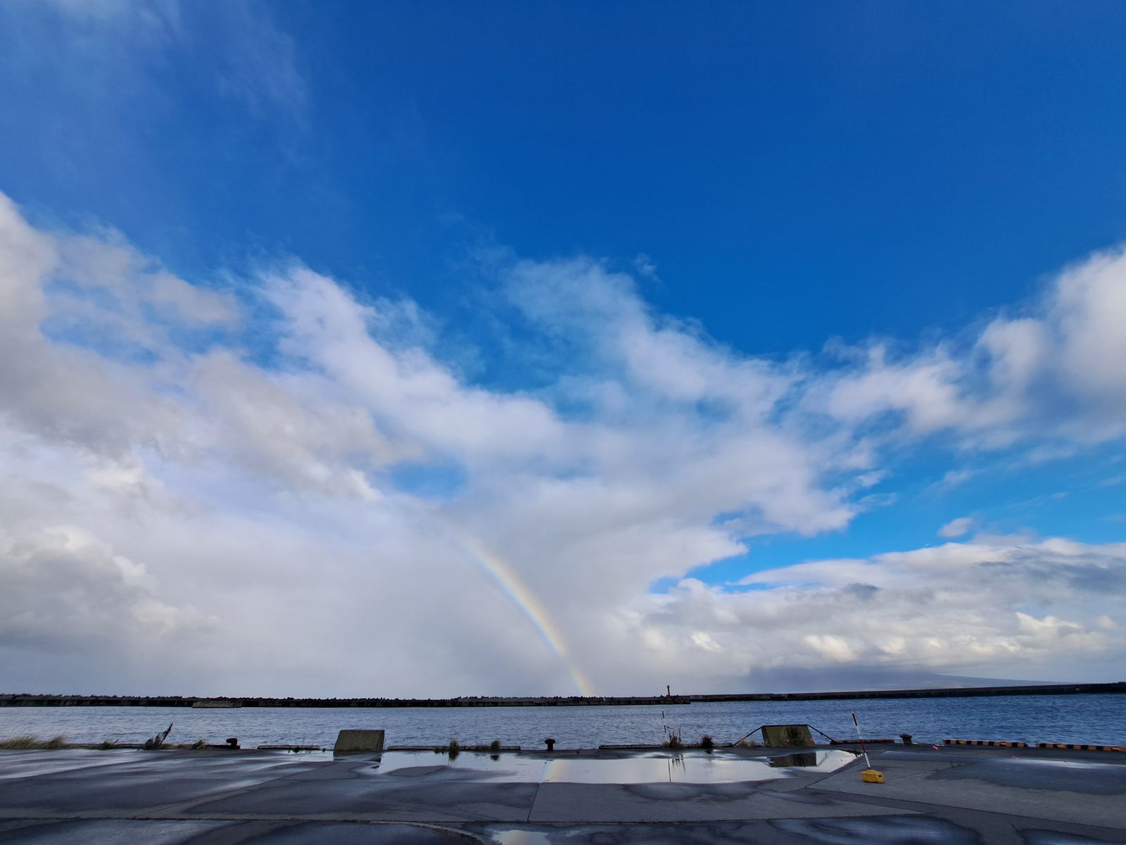 A rainbow over the port under scattered clouds